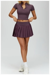 Detail of a dark purple pleated sports skirt and half-zip crop top athletic set