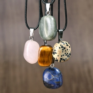 Detailed cluster of five irregular natural stone pendants on black cords over wood background