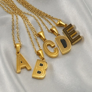 Five gold stainless steel necklaces with black enamel A-E letter pendants on silk fabric