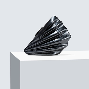 Detailed close-up of a shell-shaped black acrylic clutch with elegant marble texture