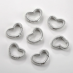 Sette chiusure in metallo argentato a forma di cuore con texture a spirale su sfondo grigio