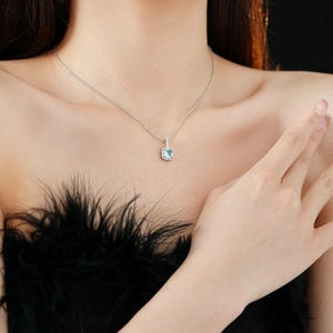 Close-up of a silver necklace featuring a square blue gemstone pendant with small diamonds