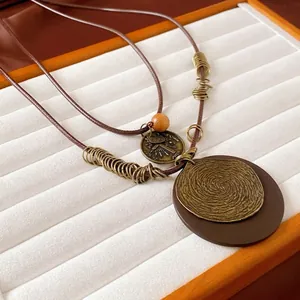 Vintage layered necklace with bronze geometric rings and coin pendant on brown cord