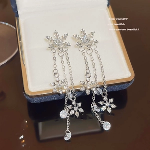 Detail showing elegant snowflake tassel earrings with silver finish and white zircons