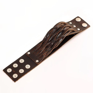 Detail of wide dark brown leather punk bracelet with braided texture and metal snap buttons