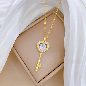 Close-up of a gold heart-key pendant with shimmering crystals on soft white silk fabric