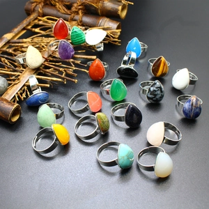 Macro detail of teardrop natural stone rings with adjustable metal bands on black surface