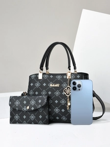 Detail of black textured PU leather handbag and matching wallet with metal KUOY logo