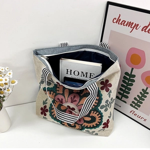 Detail of vintage floral embroidered canvas tote bag with striped handles and zipper