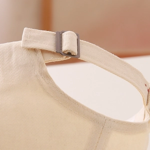 Detail view of the beige canvas hat with adjustable dark grey metal buckle at the back