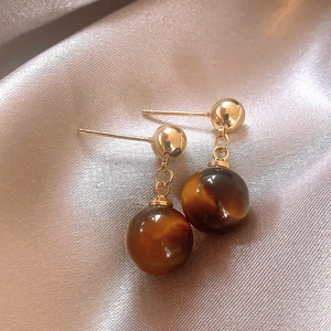 Elegant gold plated tiger eye stone drop earrings on champagne silk background