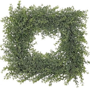 Macro detail of square boxwood wreath with lush green artificial leaves on white background