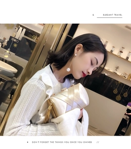 Detail of champagne gold evening clutch featuring cross-weave texture and metal tassel
