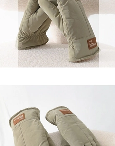 Detail of warm light khaki winter mittens with elastic cuffs and a leather brand label