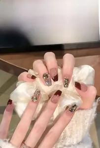 Close-up of burgundy French press-on nails with luxury rhinestones and glitter finish