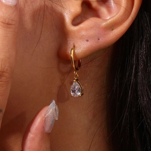 Primer plano de un aro chapado en oro con una circonita en forma de lágrima en la oreja