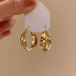 Minimalist gold intertwined layered hoop earrings on display card with metallic luster