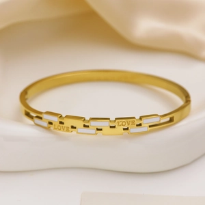 Detailed macro view of the gold titanium bracelet with white enamel and LOVE engraving