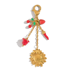 Détail d'un fermoir mousqueton doré avec breloques de fraise, cerise et tournesol