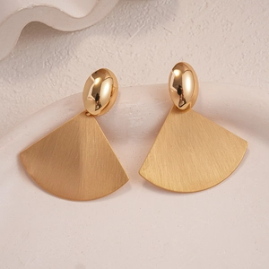 Detailed close-up of golden geometric fan earrings with polished and matte textures