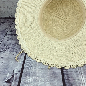 Detail of cream straw hat featuring intricate scalloped edges and inner comfort sweatband