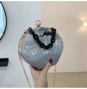 Detail of shell-shaped clutch with gray marble texture, gold frame and black chain handle