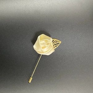 Detail of handmade cream satin rose lapel pin with a gold leaf on a long suit needle