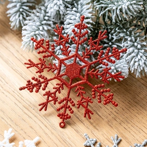 Ornamento a fiocco di neve rosso scintillante su ramo di pino e sfondo in legno