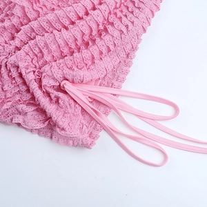 Vue détaillée du tissu en dentelle rose avec plis délicats et cordon de serrage
