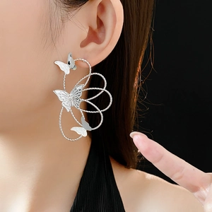 Close-up of model wearing silver hollow flower and butterfly drop earrings for women