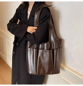 Detail of dark brown tote bag showing smooth leather texture and practical front pocket