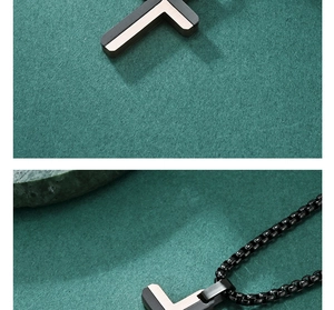 Macro detail of two-tone stainless steel cross pendant on a black chain necklace