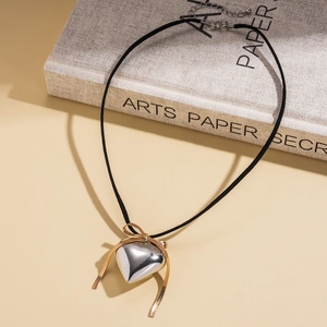Detail shot of heart and bow pendant necklace resting on a textured art book