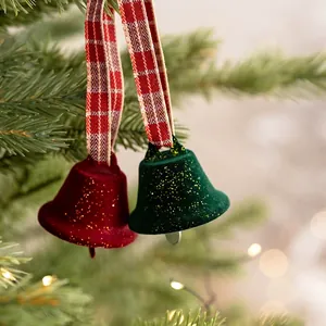 Red and green flocked Christmas bells with checkered ribbons hanging on a tree