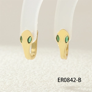 Macro shot of gold snake hoop earrings featuring green gemstone eyes and detailed scales
