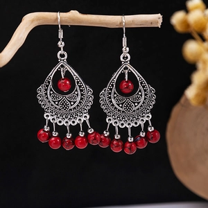 Detail view of Bohemian tassel earrings with red beads and vintage silver carvings