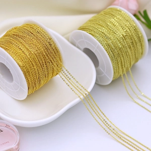Macro shot of two rolls of 18K gold plated jewelry chains on white plastic spools