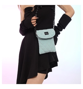 Close-up of light green quilted small crossbody bag with a Fashion woven label