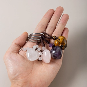 Detailed close-up of heart-shaped rose quartz, amethyst and tiger eye woven keychains