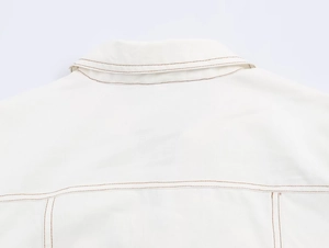 Détail du col arrière blanc avec surpiqûres marron contrastées sur tissu de qualité