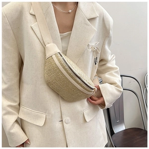 Detail view of beige woven straw waist bag with cream PU leather trim and canvas strap