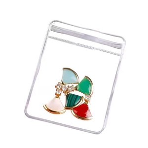 Colorful fan-shaped jewelry pendant in a clear protective pouch with gold metal base