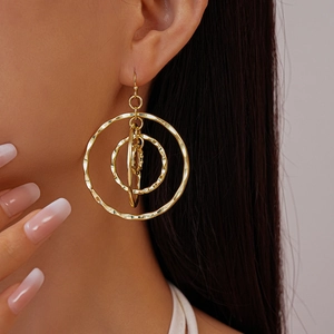 Macro detail of golden hollow circular textured earrings with hammered metal finish on model