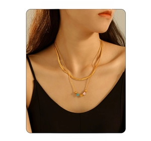 Double-layered gold snake chain necklace with three colorful enamel heart charms on a model