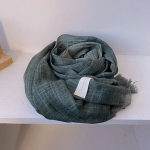Close-up of dark green gradient cotton scarf with fringe and vintage woven label