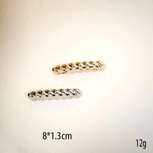 Detail view of gold and silver twisted metal hair clips measuring 8x1.3cm on beige background