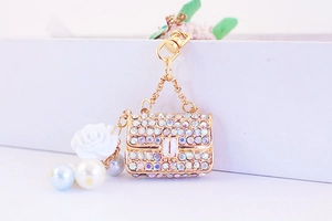 Detail of golden purse keychain with white resin camellia flower and pearl accents