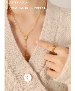 Detail of gold-plated saint medal and cross pendant necklace with a knot ring on model