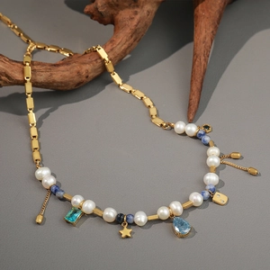 French retro gold chain necklace with pearls, blue stones, and star charm on wood