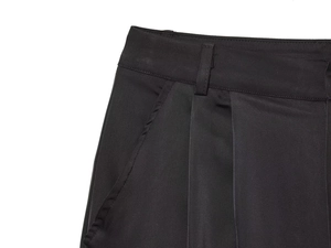 Detailed close-up of the waistband, belt loops and side pockets on black satin trousers